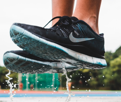 Black Nike running shoes jumping over a fountain.